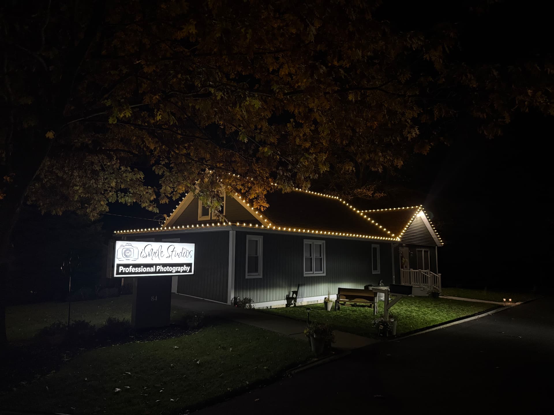iSmile Studios building at night with warm-white C9 Christmas lights outlining the rooflines and gables