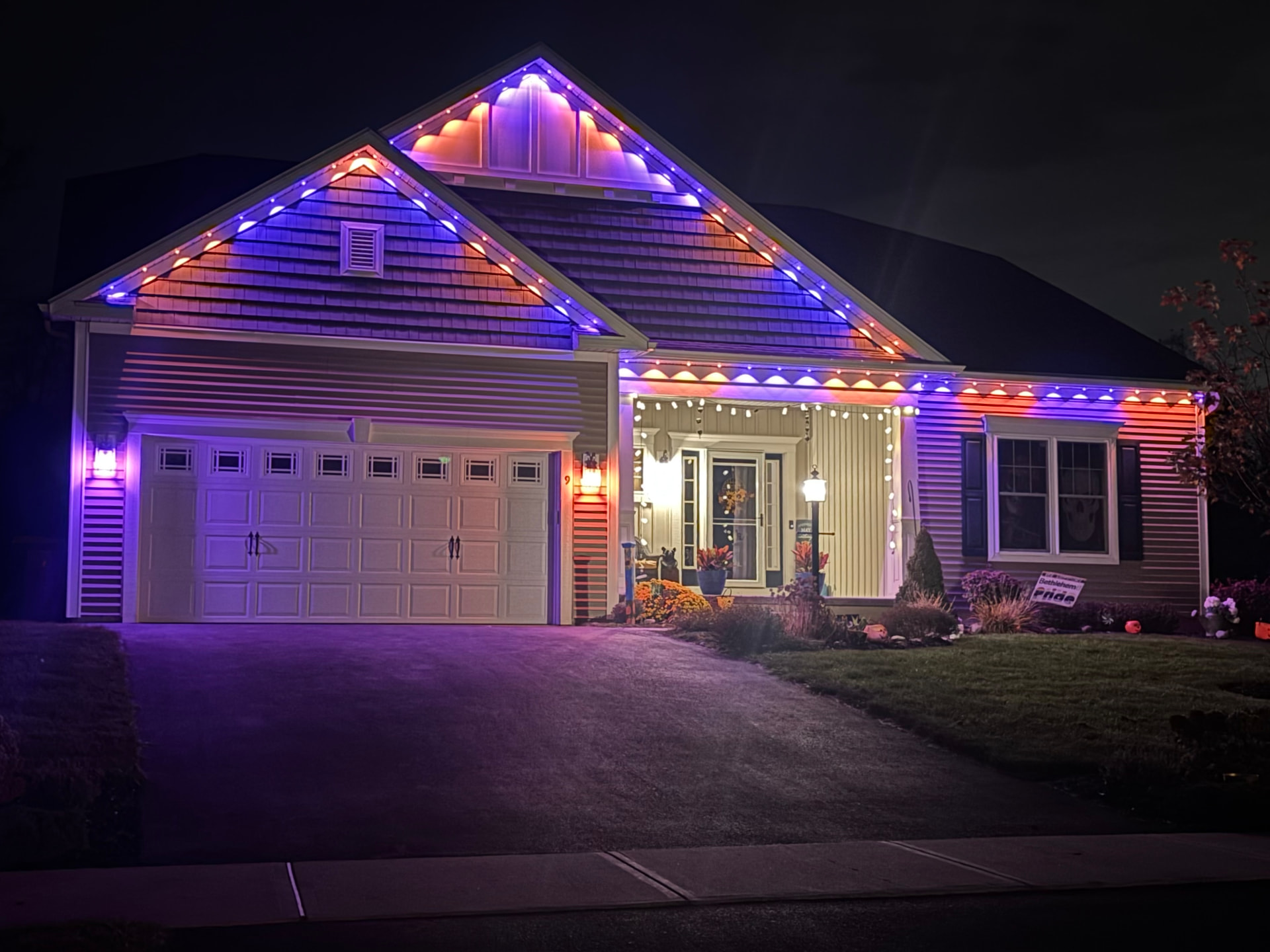 Front of a home at night with permanent color-changing lights along the gables and eaves